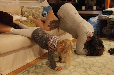 Birthing person and 4 year old doing a forward leaning inversion off the sofa during labor. 